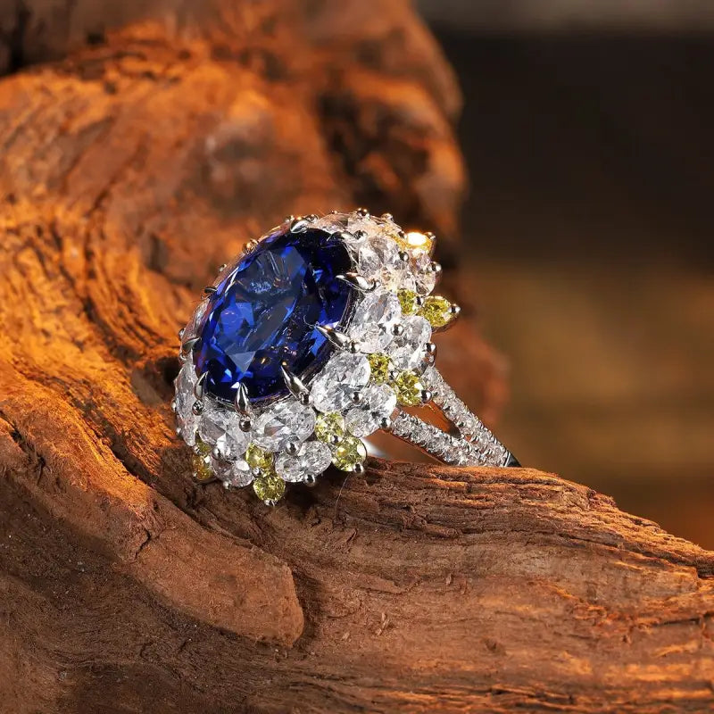 Ornate ring featuring a large oval blue gemstone surrounded by smaller white and yellow stones.