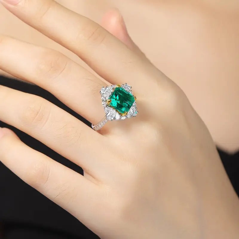 Emerald and diamond ring on a person’s finger.