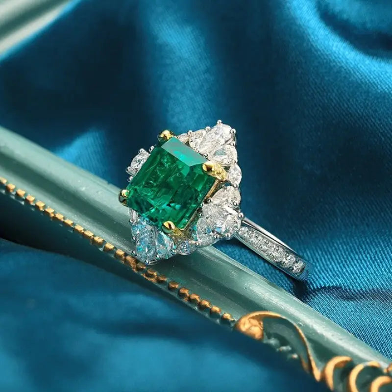 Emerald and diamond ring with a square-cut green gemstone as the centerpiece.