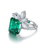 Load image into Gallery viewer, Emerald-cut green gemstone ring with diamond accents in a floral design.
