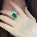 Load image into Gallery viewer, Emerald-cut green gemstone ring with diamond accents.
