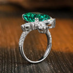 Load image into Gallery viewer, Ornate silver ring featuring a prominent emerald-green gemstone surrounded by smaller diamonds.
