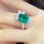 Load image into Gallery viewer, Emerald-cut green gemstone ring with diamond accents.
