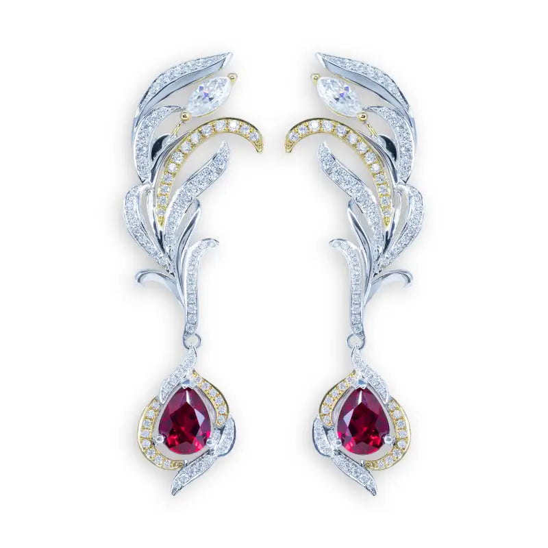 Pair of ornate feather-shaped earrings with dangling ruby-colored gemstones.