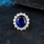 Load image into Gallery viewer, Sapphire and diamond ring with an oval blue gemstone surrounded by white diamonds.
