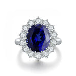 Load image into Gallery viewer, Sapphire and diamond ring with an oval-cut center stone surrounded by a halo of round diamonds.
