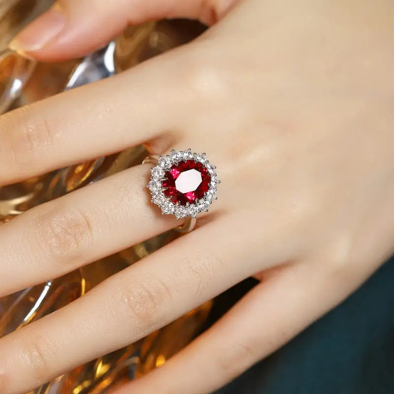 Ruby and diamond cluster ring on a finger.