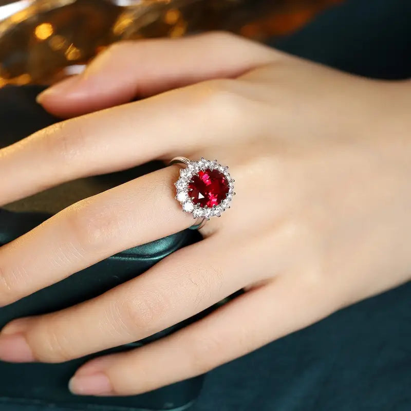 Ruby and diamond halo ring on a person’s finger.