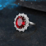 Load image into Gallery viewer, Ornate ring featuring a deep red gemstone surrounded by smaller white diamonds.
