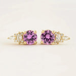 Load image into Gallery viewer, Pair of gold earrings featuring purple gemstones flanked by smaller clear stones.
