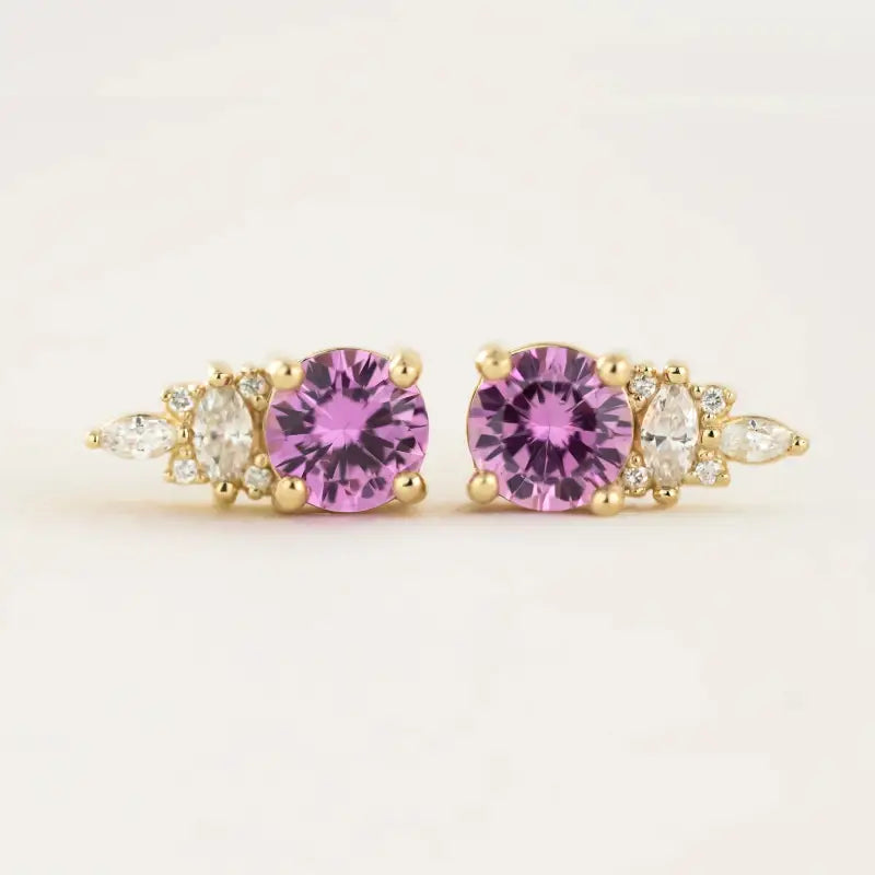 Pair of gold earrings featuring purple gemstones flanked by smaller clear stones.