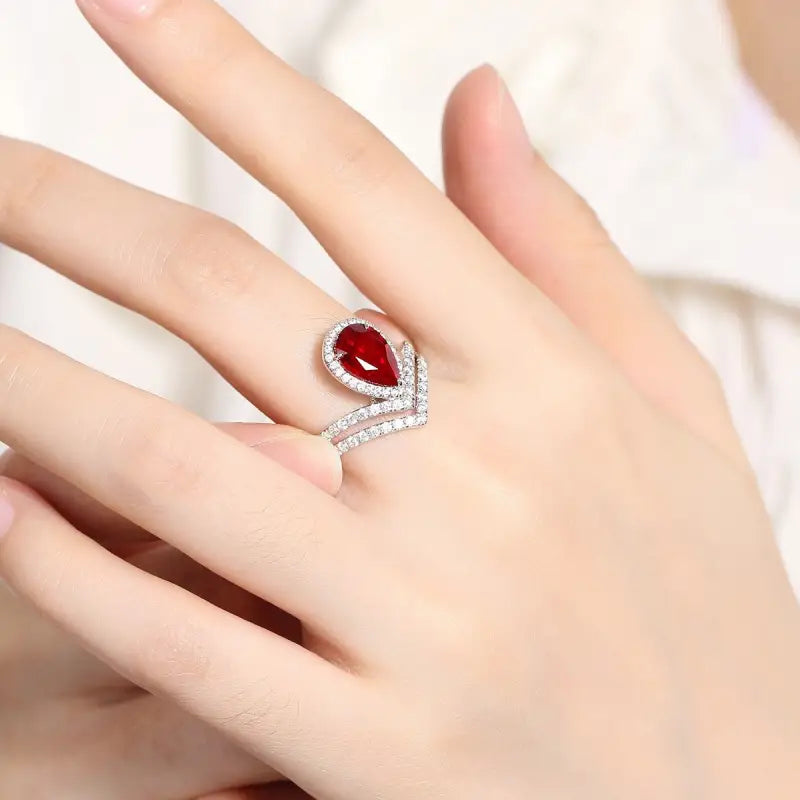 Elegant ring featuring a teardrop-shaped red gemstone surrounded by diamond accents.