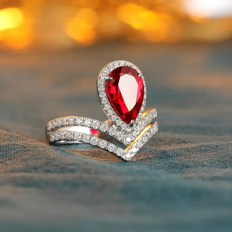 Elegant ring featuring a pear-shaped ruby surrounded by diamonds in a unique V-shaped design.