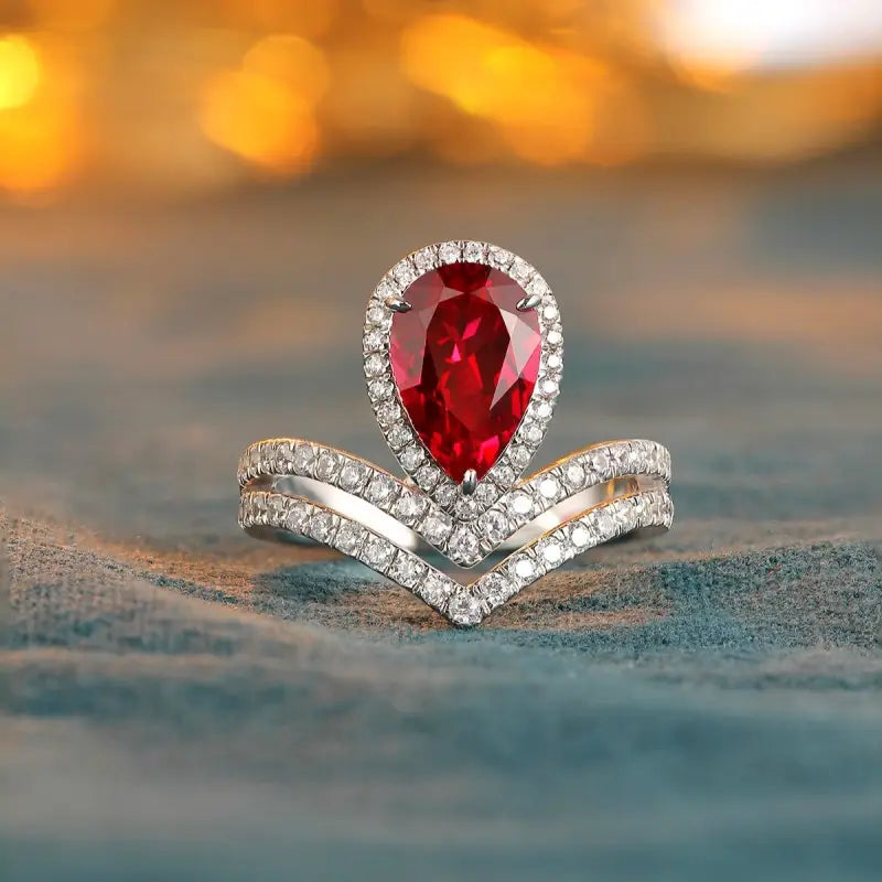 Elegant ring featuring a pear-shaped ruby surrounded by diamonds in a chevron setting.