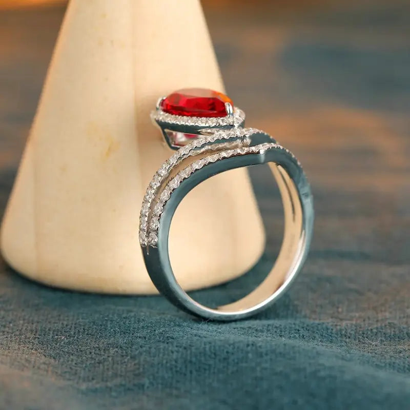 Elegant silver ring featuring a prominent red gemstone surrounded by smaller diamonds.