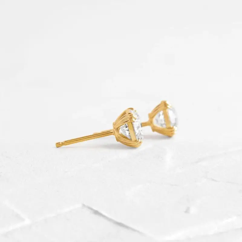 Gold stud earrings with triangular clear gemstones.