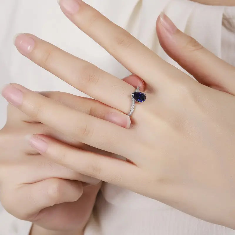 Ring with a blue gemstone on a person’s finger.