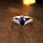 Load image into Gallery viewer, Elegant engagement ring featuring a pear-shaped blue sapphire surrounded by diamonds on a silver band.
